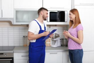 Housewife and repairman near microwave oven in kitchen